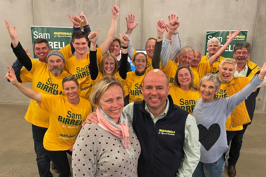 Sam Birrell and his wife Lisa smile as they stand together in front of supporters.