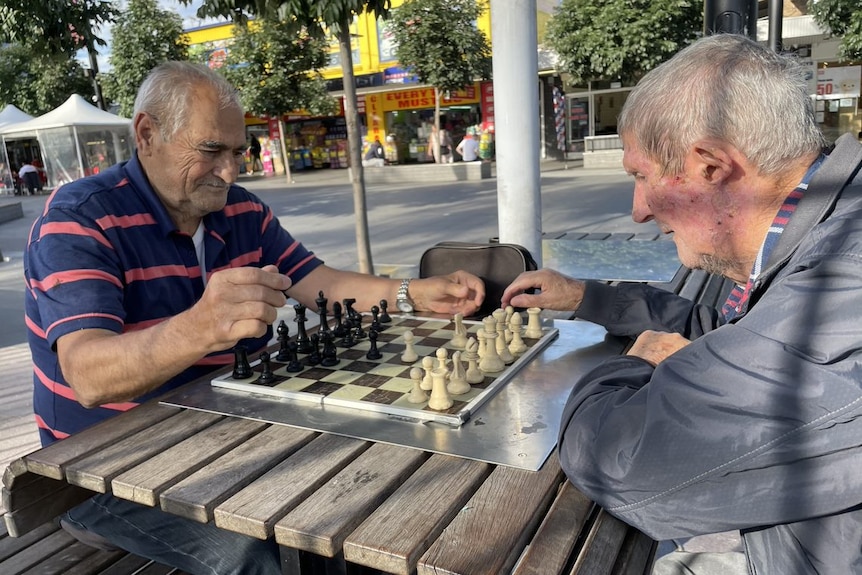 Two older man playing chess in a pedestrian zone