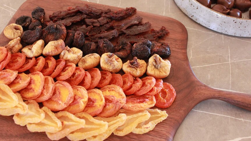 A wooden board with a variety of dried fruit on it
