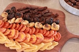 A wooden board with a variety of dried fruit on it