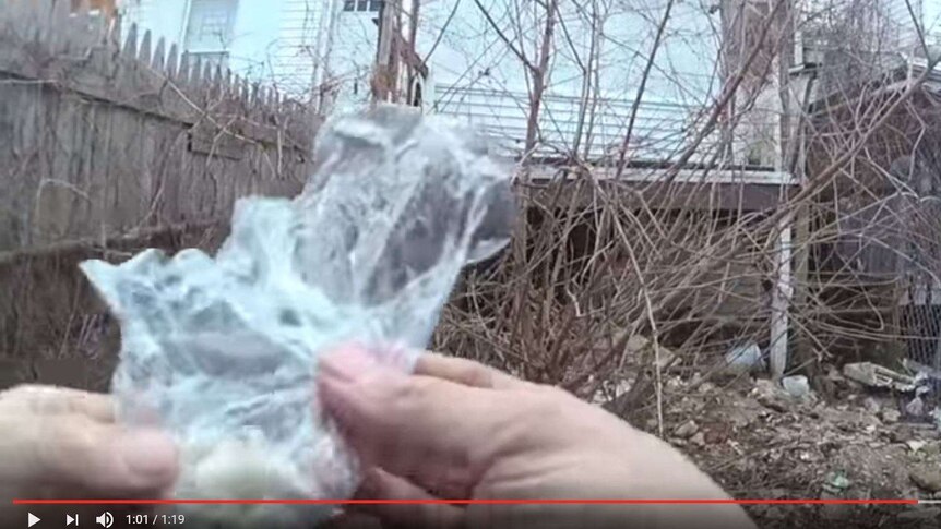 Video still shows pair of hands handling plastic bag