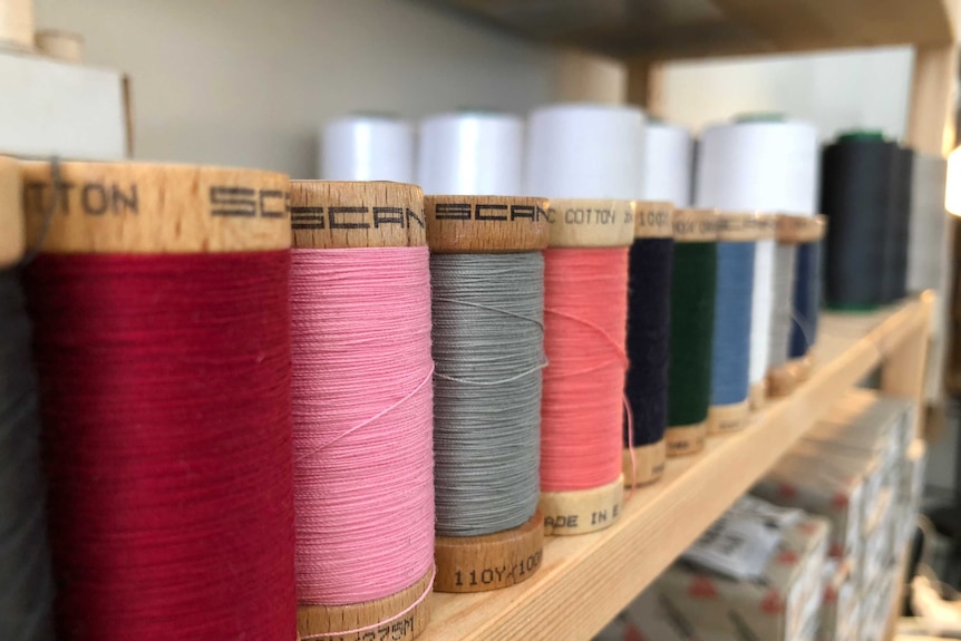 close up shot of a row of colourful threads on wooden spools