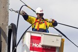 Worker in a cherry picker installs national broadband wires in a Tasmanian town