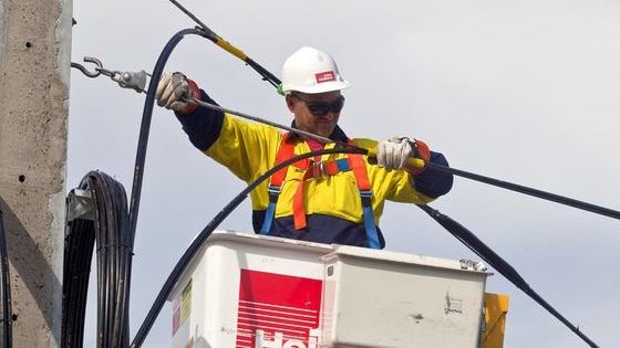 Worker in a cherry picker installs national broadband wires in a Tasmanian town