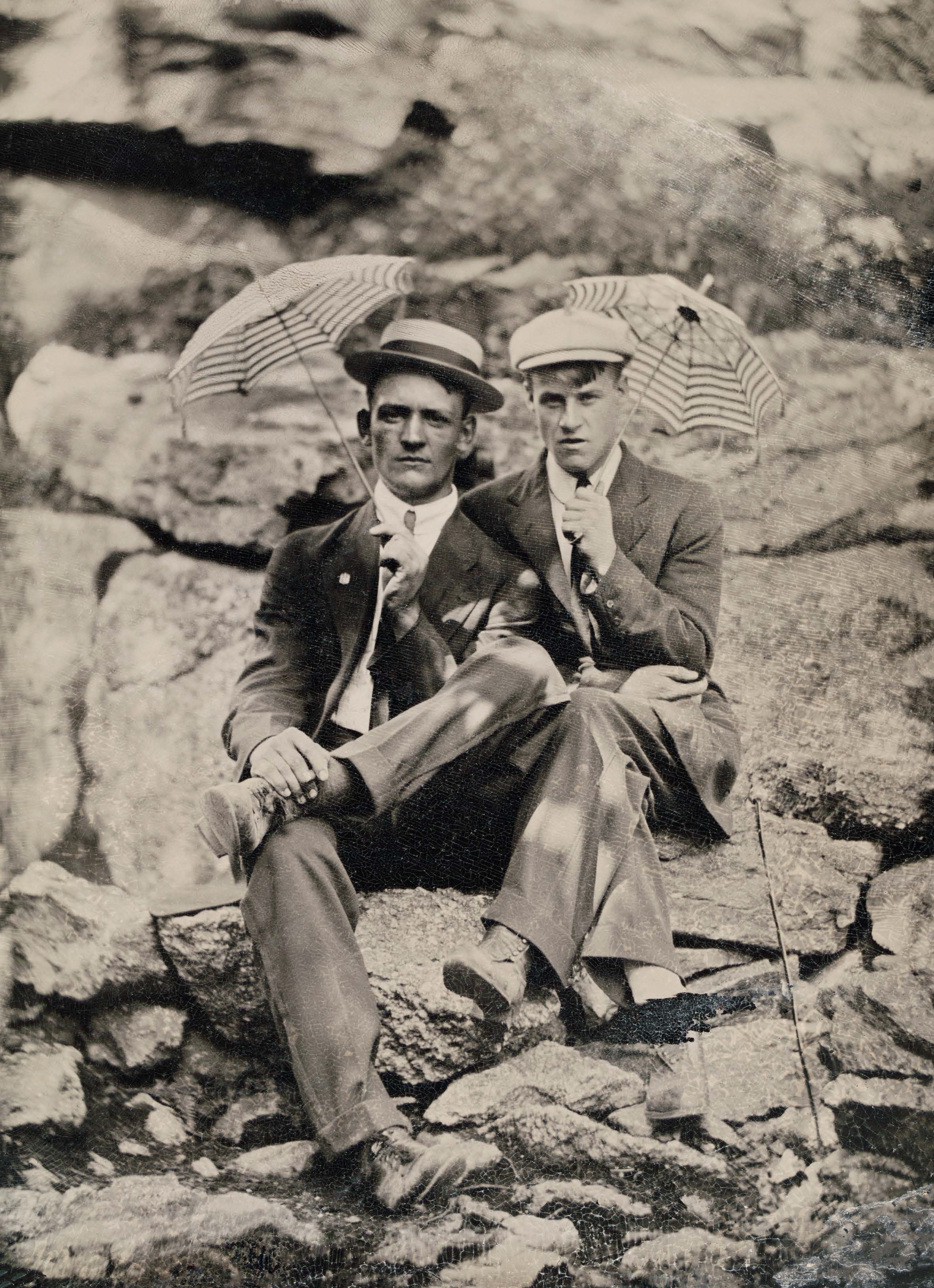 Dos hombres se sientan juntos y sostienen pequeños paraguas.