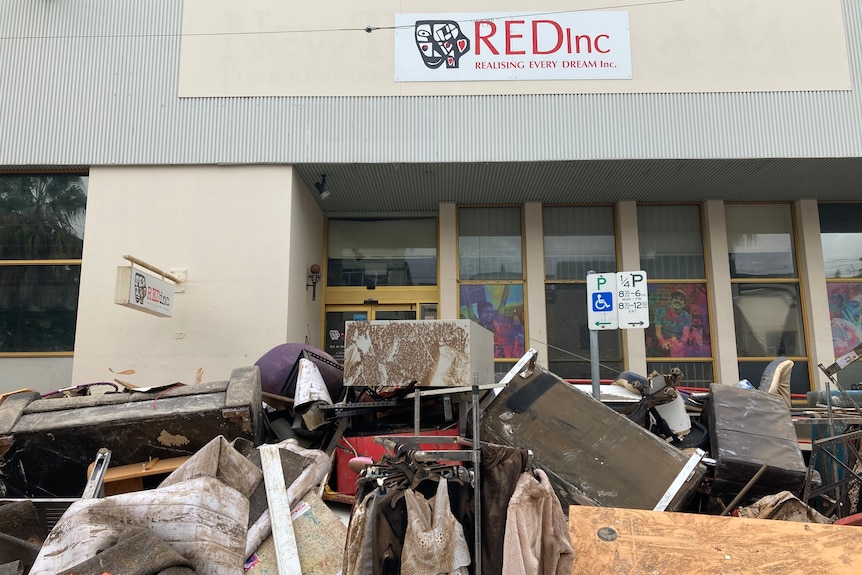 A building with a sign that says REDInc Realising Every Dream, and a pile of rubbish out the front.