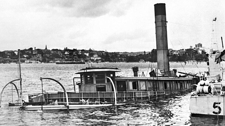 HMAS Kuttabul sits partly submerged in the waters of Sydney Harbour next to the dock at Gardens Point.