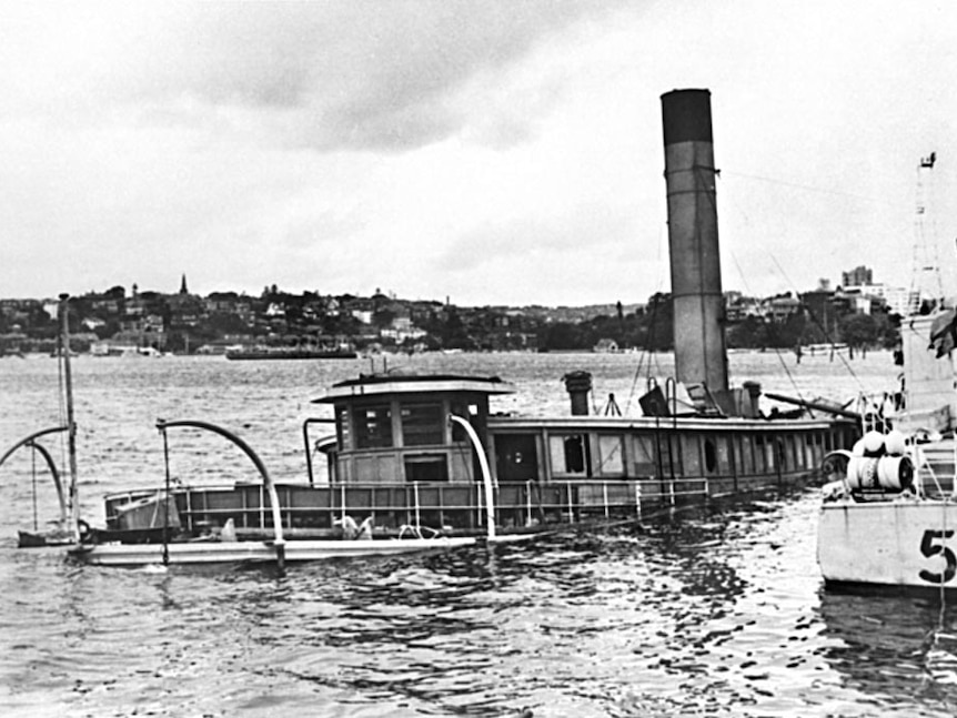 HMAS Kuttabul sits partly submerged in the waters of Sydney Harbour next to the dock at Gardens Point.