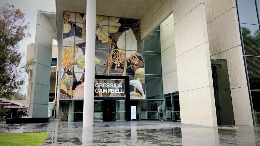 The entrance to a large building with a flower mural on exterior wall saying Cressida Campbell. 
