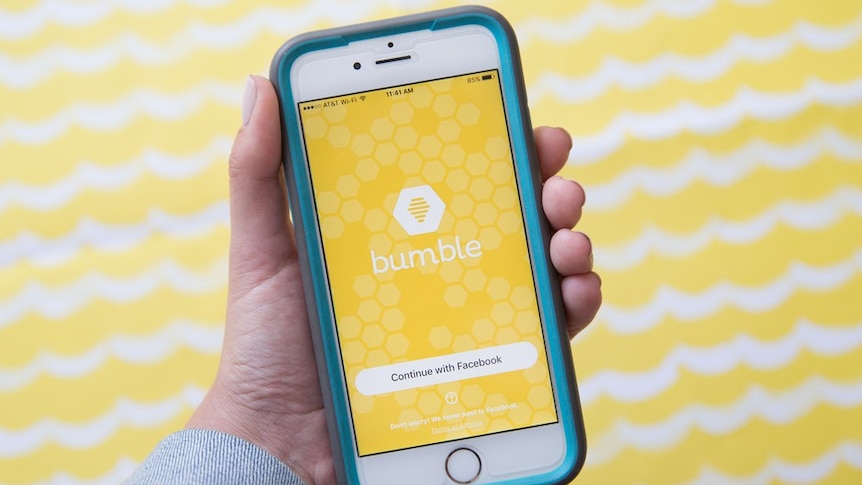 Hand holding an iPhone showing the Bumble app