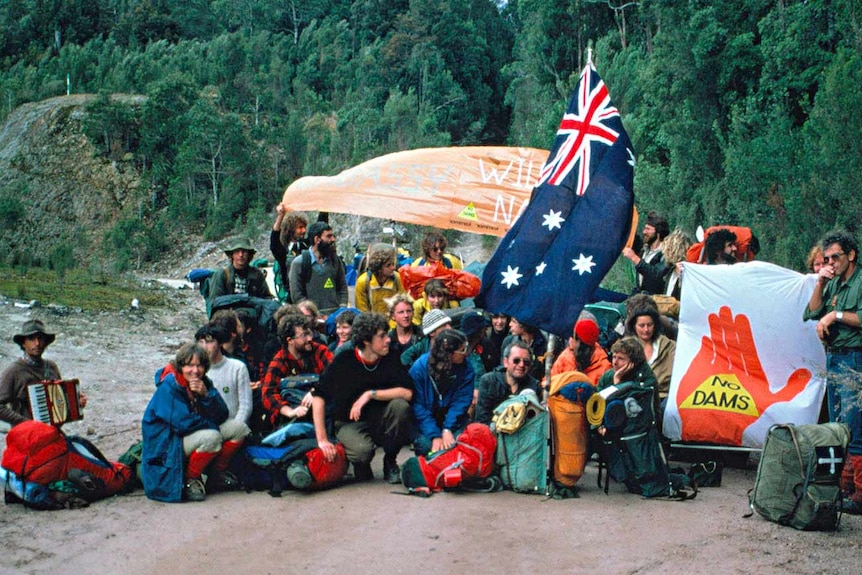 A group of protesters out front of the forest holding signs and flags.
