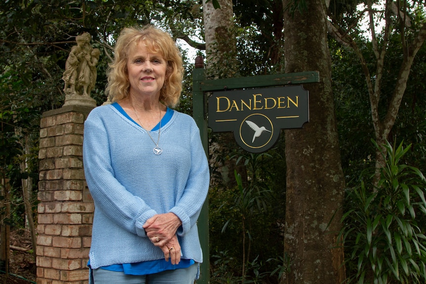 A woman in blue stands in front of a sign that says 'dan Eden'