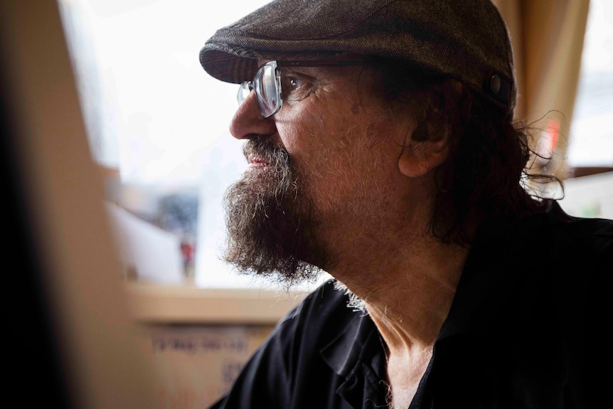 A close up side profile of a man's face, wearing glasses and a cap.