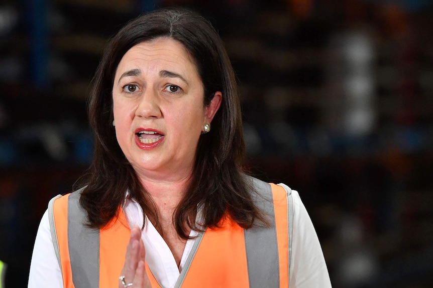 Headshot of Annastacia Palaszczuk speaking to the media, wearing a high-vis shirt in a factory.