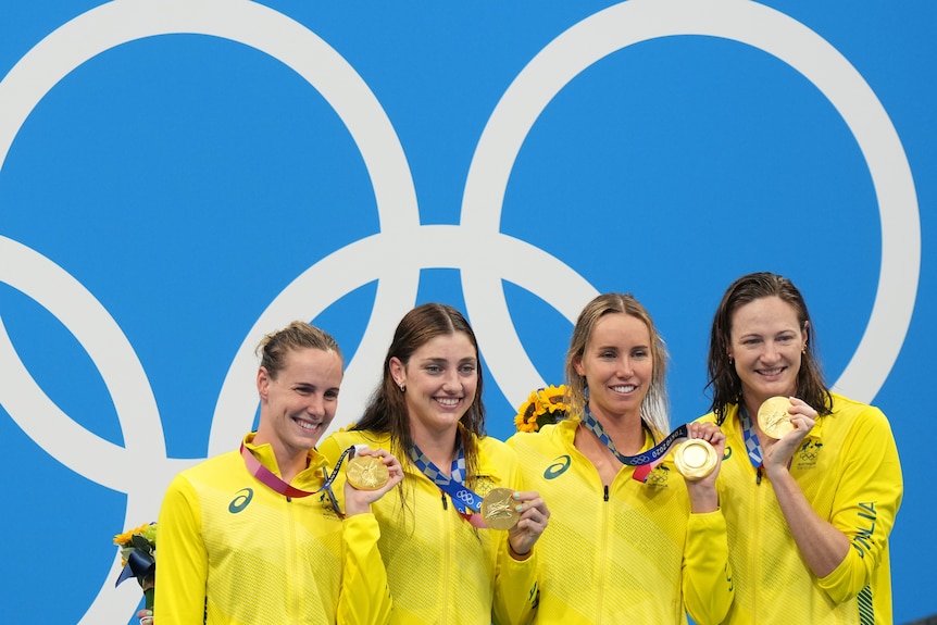Four female swimmer on the medal podium after winning gold in the 4x100m relay