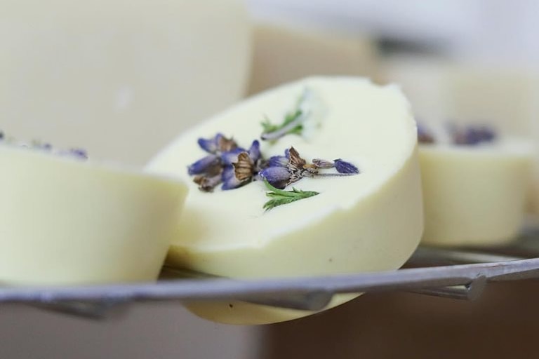 A circular bar of white soap with a sprig of lavender