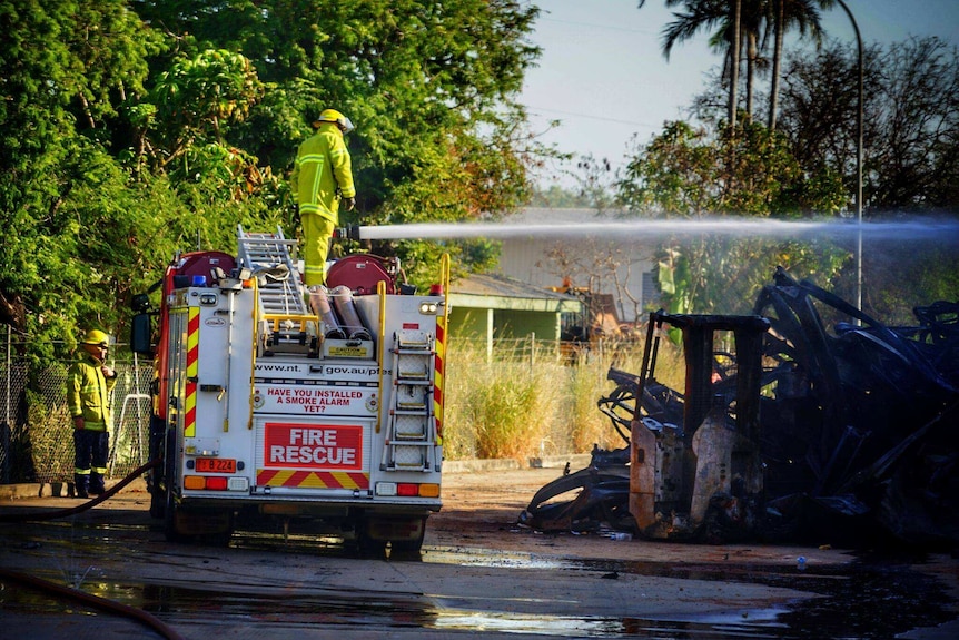 A firefighter stands on a truck and a jet of water is ejected