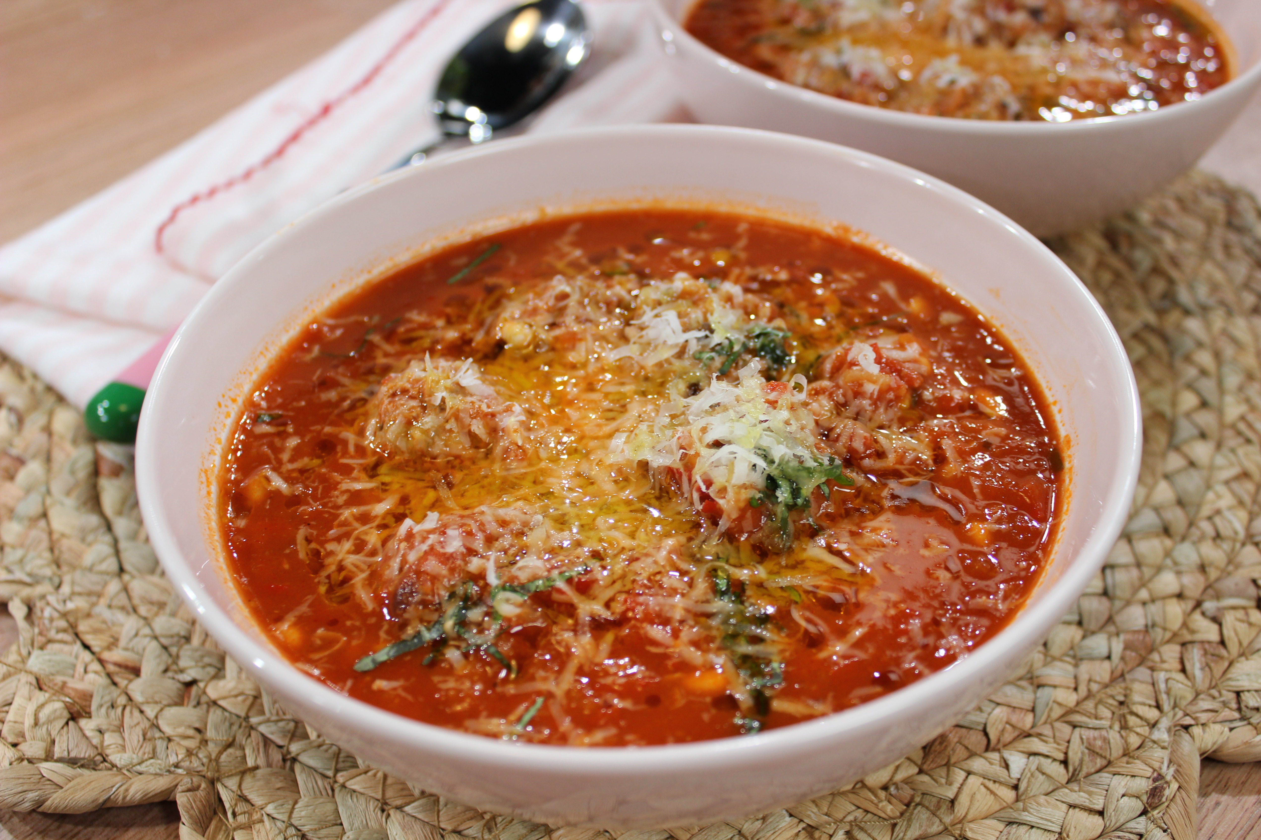 Una imagen de albóndigas de salchicha de puercoespín en un plato de sopa de tomate con queso.