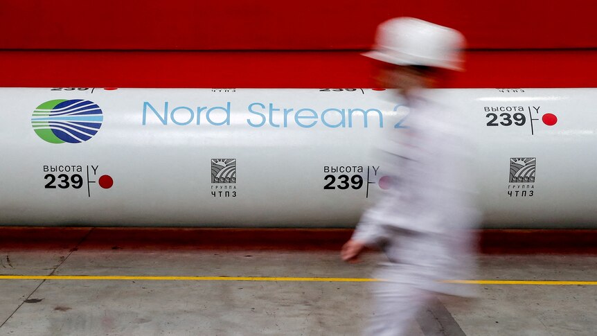 A Nord Stream 2 gas pipe in front of a red wall
