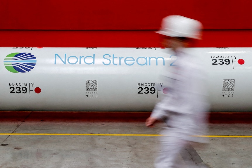 A Nord Stream 2 gas pipe in front of a red wall