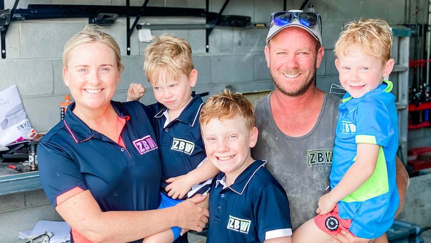 A man and woman smiling with their three sons