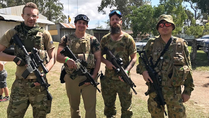 Four men dressed in camouflage clothing each hold a gel ball blaster for a game at Pimpama facility.