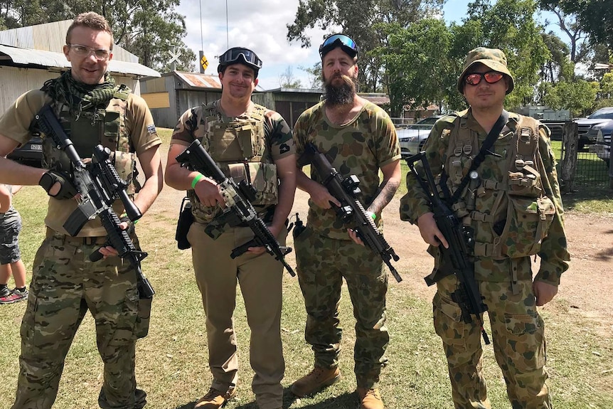Four men dressed in camouflage clothing each hold a gel ball blaster for a game at Pimpama facility.