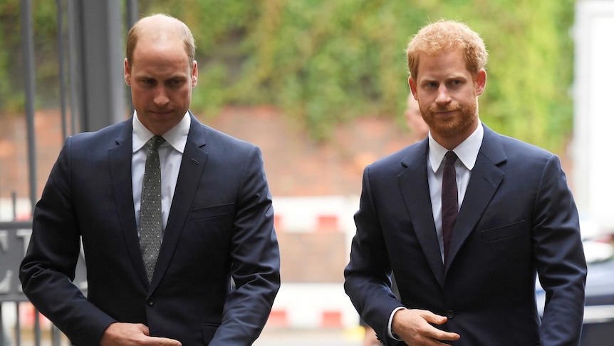 Britain's Prince William, the Duke of Cambridge, left, and Prince Harry wearing dark coloured suits.