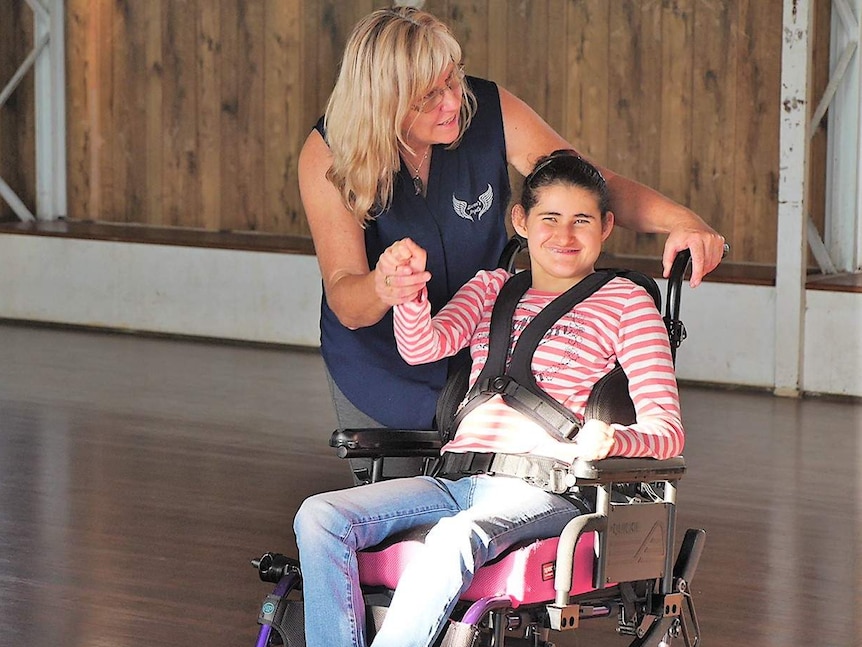 A young woman in a wheelchair with an older woman who is her carer.