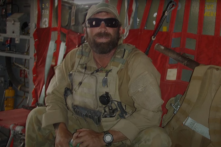 a soldier in uniform sitting in a military aircraft