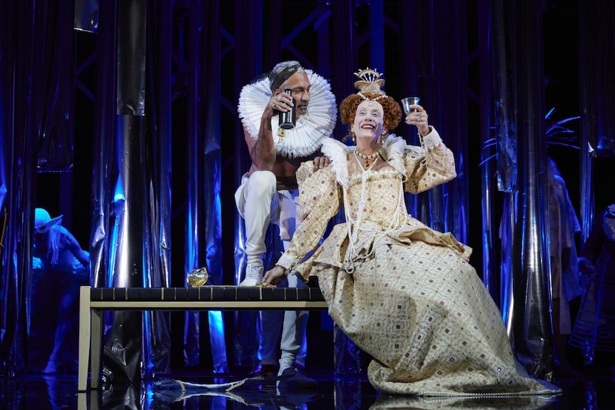 A woman dressed as Elizabeth I and a man wearing an Elizabethan frill on stage.