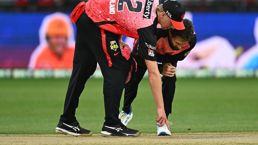 Melbourne Renegades players point at the pitch during a Big Bash League game.
