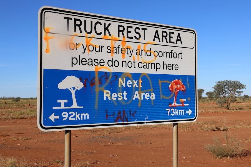 Un panneau routier dégradé avec de la terre rouge en arrière-plan