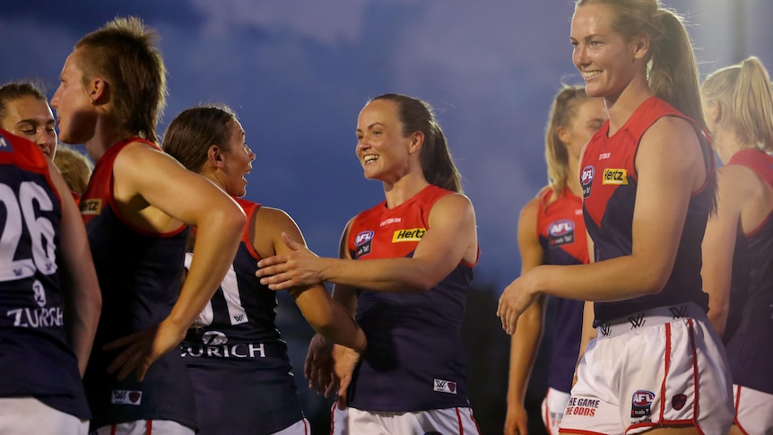 Daisy Pearce shakes hands and smiles with Melbourne Demons teammates after an AFLW win over Richmond.