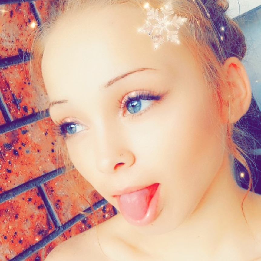 A screenshot from a Snapchat message of a teenage girl. She is using a filter that adds snowflakes and sparkles to her head.