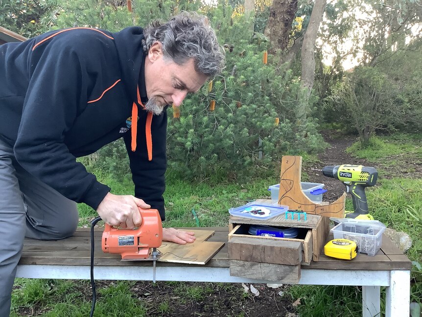 Man with electric saw building a puzzle box.