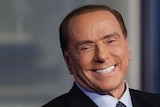 A head and shoulder picture of Silvio Berlusconi wearing a suit and smiling.