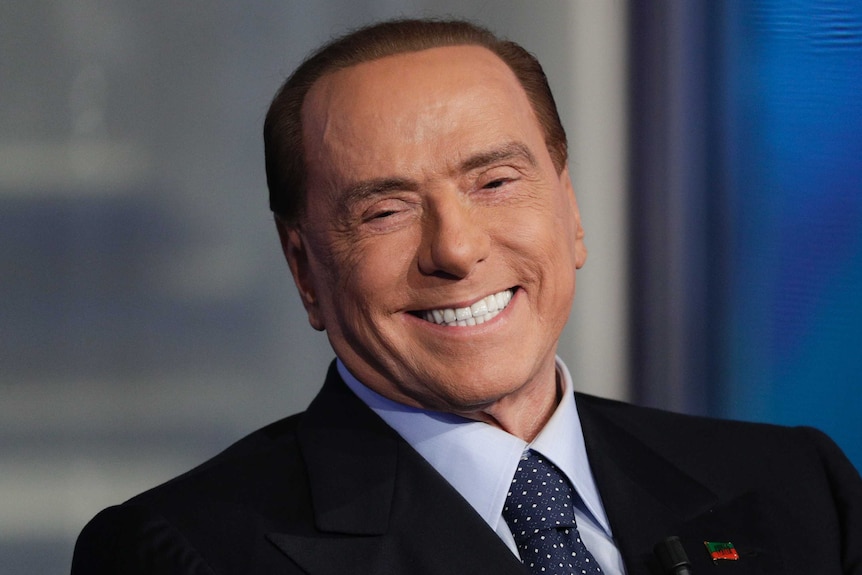 A head and shoulder picture of Silvio Berlusconi wearing a suit and smiling.