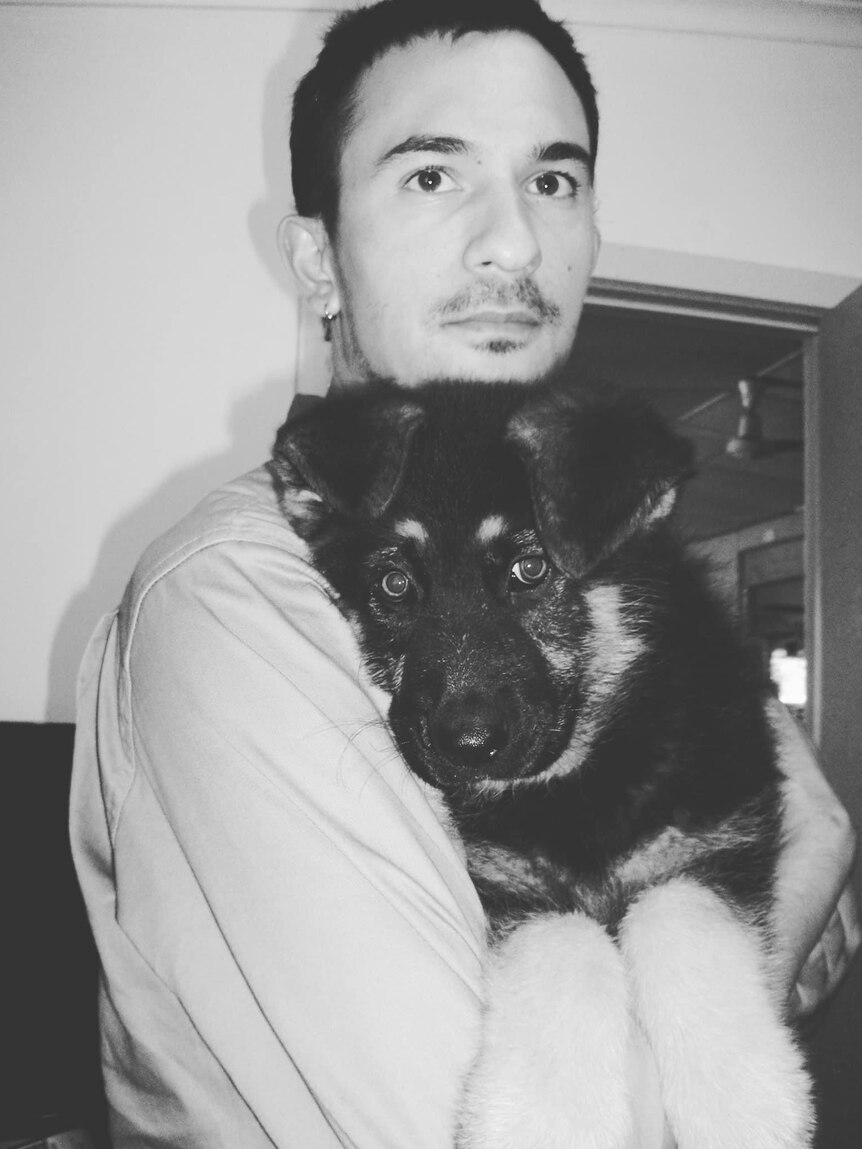 A black and white photo of a man holding a dog in his arms