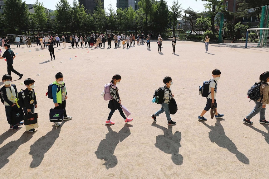 Students wearing face masks as a precaution against the new coronavirus walk to their classrooms in Seoul.
