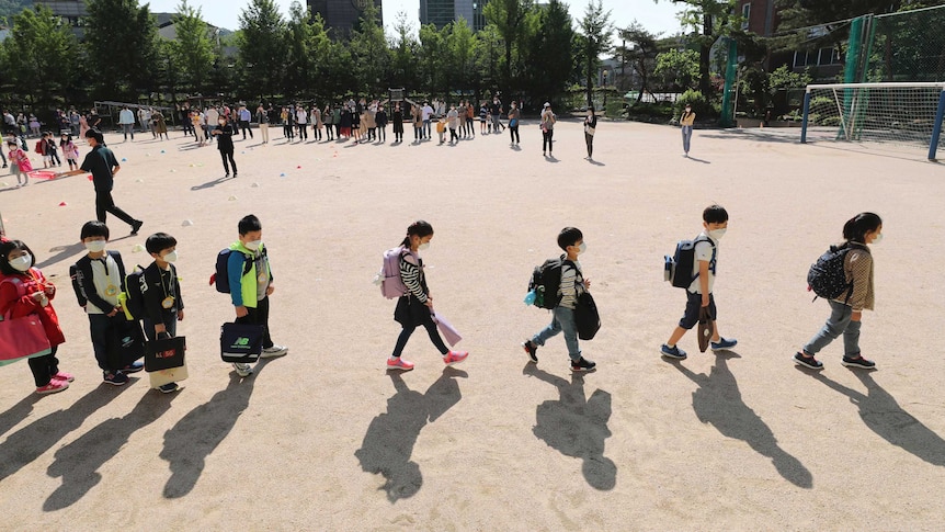 Students wearing face masks as a precaution against the new coronavirus walk to their classrooms in Seoul.