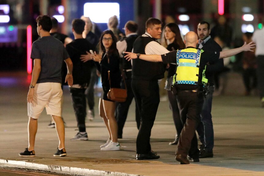 A Police officer clears people away from the area near London Bridge.