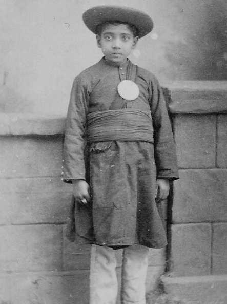 An old photo of a young Indian boy wearing clothing of the late 1800s