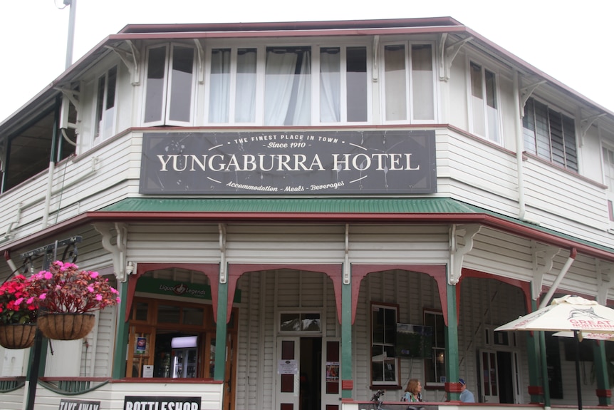 A sign attached to an old white building that says since 1910 the  Yungaburra Hotel
