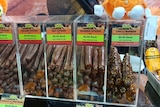Plastic display cases packed with salami sticks and other cured meat treats.