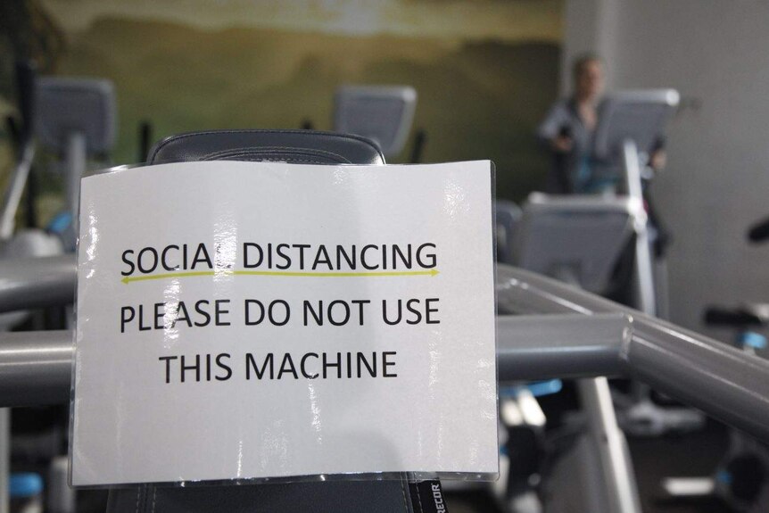 Treadmill with sign that says: "Social distancing please do not use this machine".