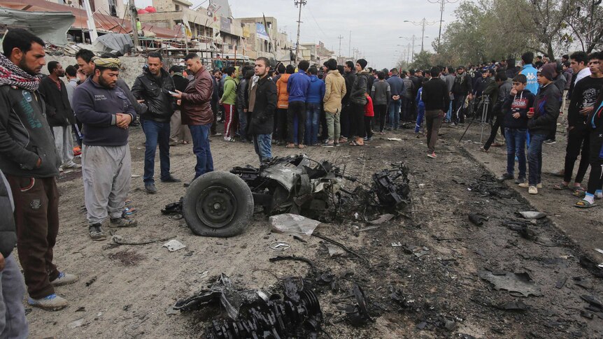 Citizens inspect the scene after a car bomb explosion at a crowded outdoor market in the Iraqi capital.