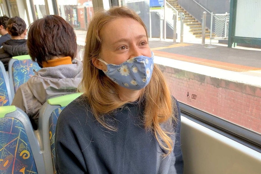 A woman wearing a face mask on a train.