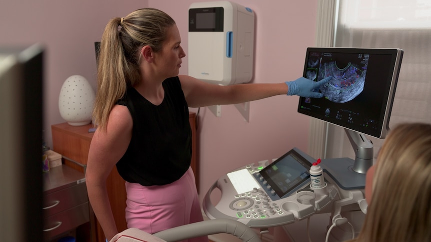 A woman points to an ultrasound screen