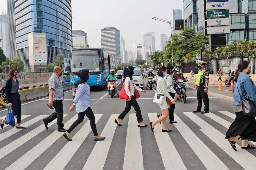 People cross a main road in Jakarta.